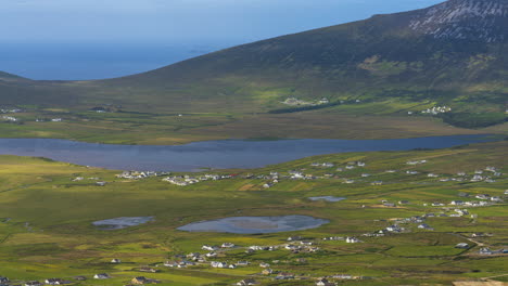 timelapse of seaside village and lake hillside landscape with clouds casting shadows in daylight viewed from minaugn heights in achill island in county mayo in ireland