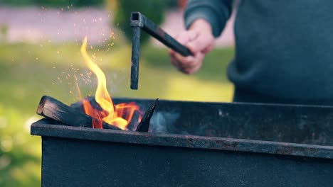 cu slow motion man pushes the burning firewood in the brazier with poker