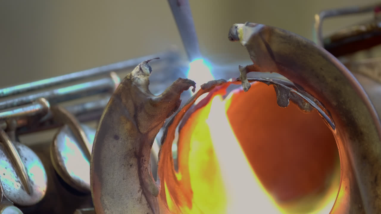 Un fabbro utilizza la saldatura a gas per fondere un sassofono di ottone, producendo scintille distruttive e fiamme dai colori vivaci