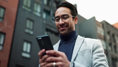 a young man smiling and looking at his phone in the city