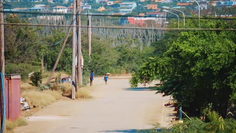 Two-young-boys-running-through-the-outer-suburban-streets-of-Bonaire,-Caribbean