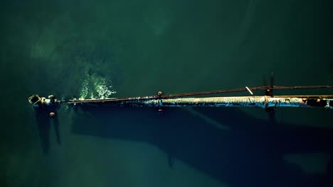 low aerial top down shot of rusty leaking pipe running into lake surrounded by mangroves, dumping sewage