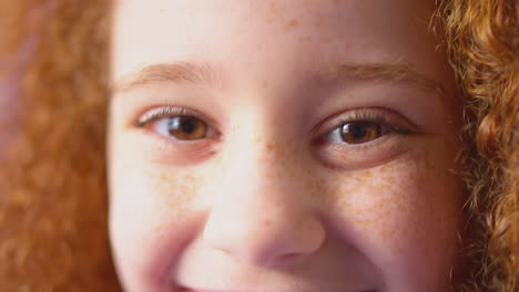 Close-Up-Studio-Portrait-Of-Smiling-Girl-With-Red-Hair-Against-Yellow-Background