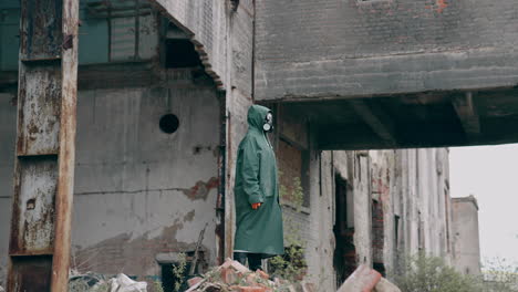 survivor in abandoned place with radiation. virologist man in protective costume and respirator gas mask stands in a deserted industrial factory background.