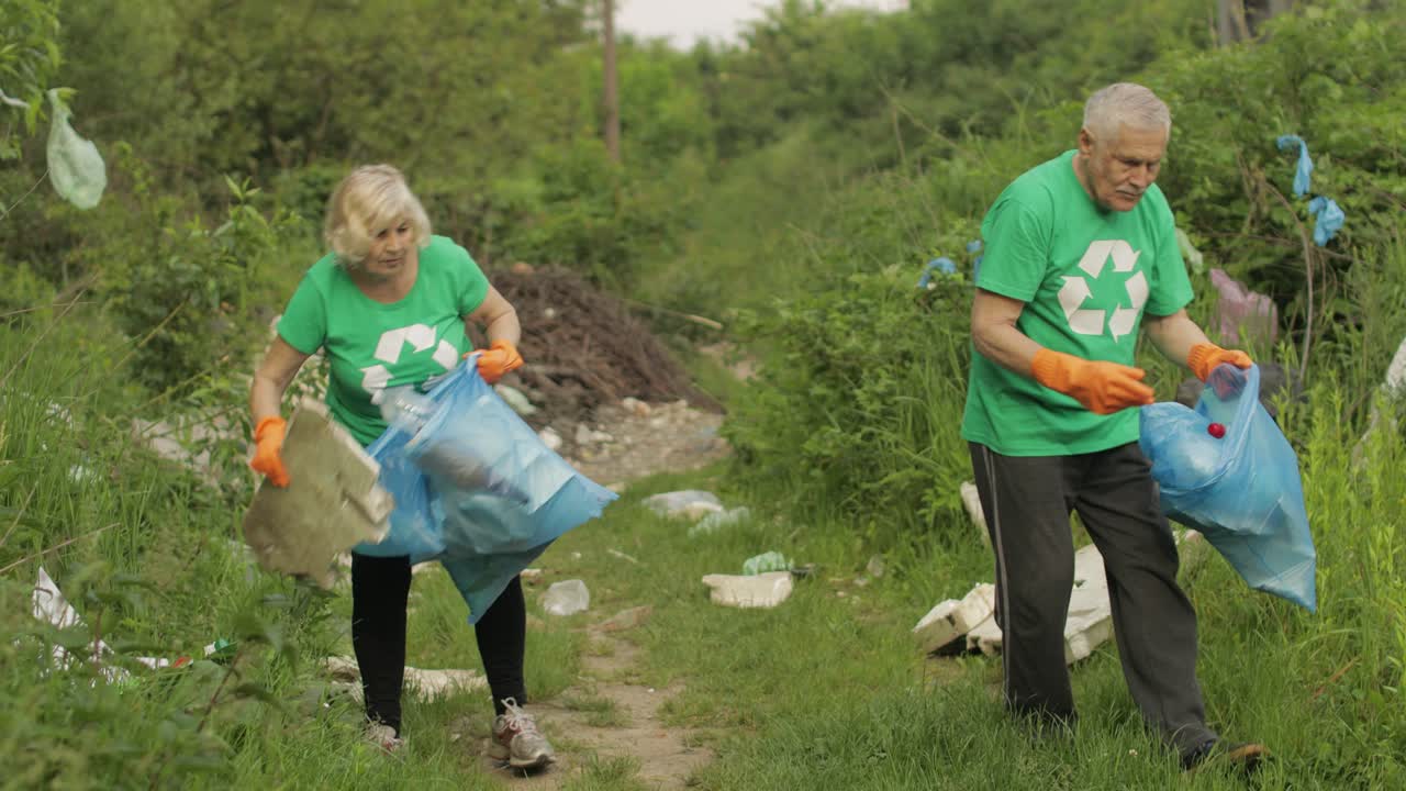 Squadra di attivisti ambientalisti con magliette ecologiche che raccolgono rifiuti di plastica nel parco. Riciclo, inquinamento del pianeta.