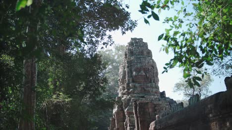 ancient angkor wat temple ruins peering through lush foliage in bright daylight