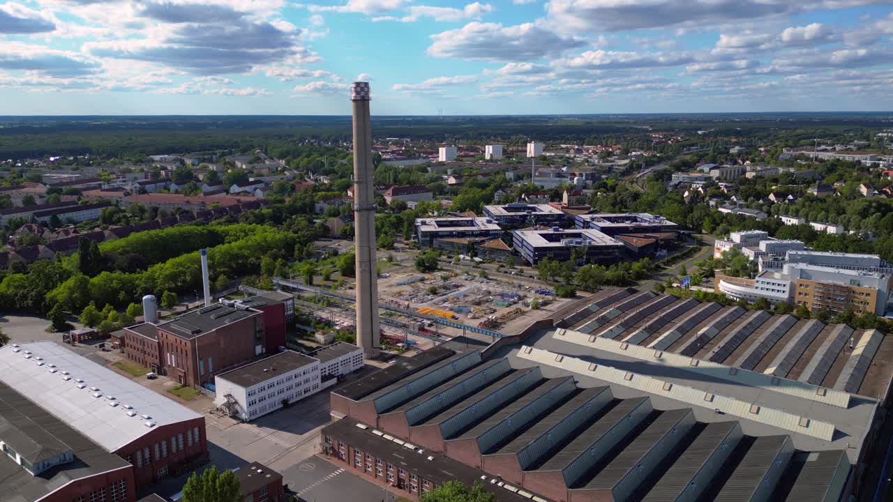 industrial buildings and a chimney in Hennigsdorf, Germany, with a train passing by. Majestic aerial view flight panorama overview drone