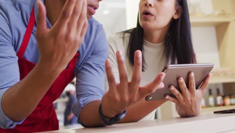 video of diverse female owner and male waiter working with tablet at cafe shop