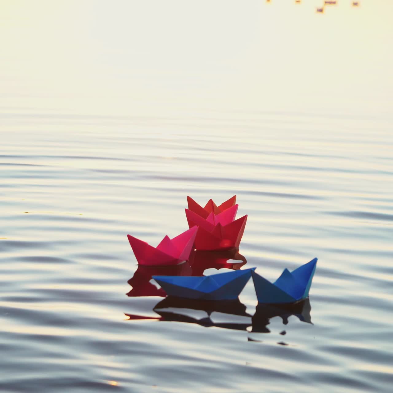 Toy paper boats on the surface water at sunset. Colored paper ships in the water