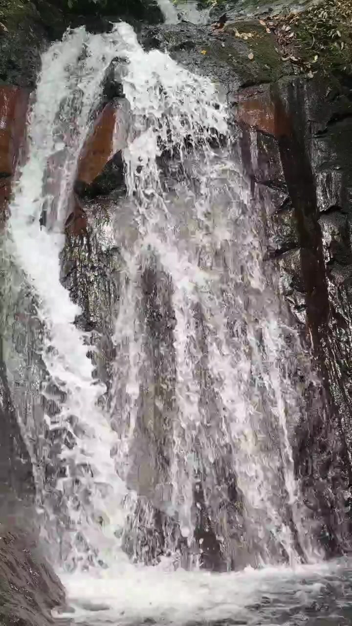 Piccola cascata che scende su una scogliera rocciosa scura