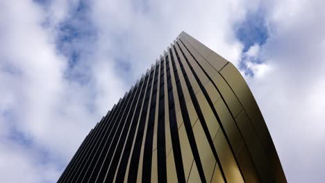 Toma-De-ángulo-Bajo-Del-Complejo-De-Edificios-Exteriores-Dorados-Con-Vista-A-Las-Nubes-Blancas