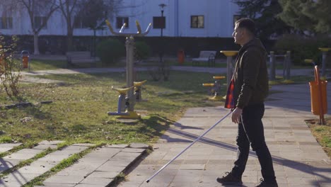 el ciego sentado en un banco se levanta y comienza a caminar.