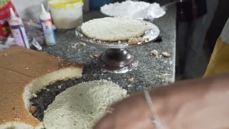 un panadero preparando las capas de bizcocho para un pastel cortándolas