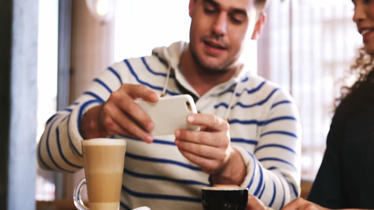 커피를 마시면서 스마트폰을 사용하는 커플