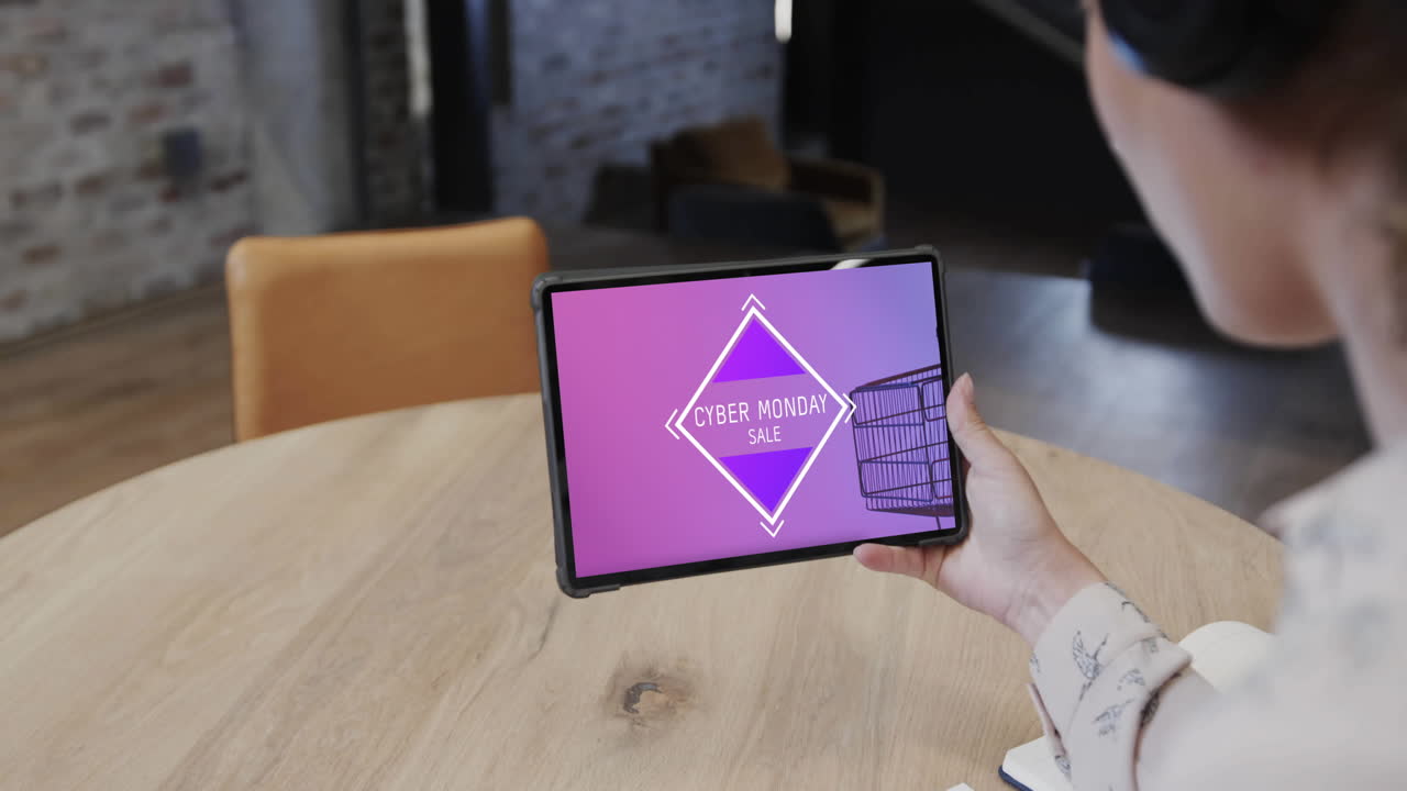 mujer biracial usando tableta en una cafetería comprando en línea en el día de venta del lunes cibernético, cámara lenta