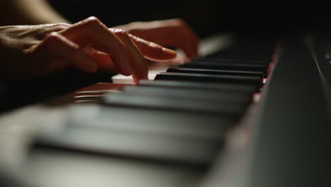 woman's hands playing piano. close up. moody lighting