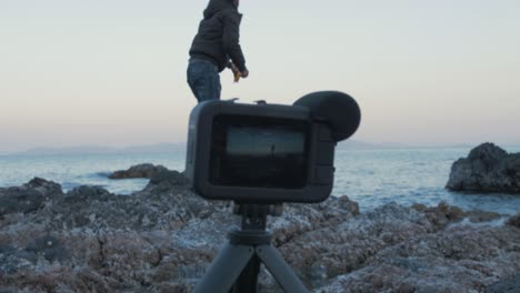 young man casting fishing line while filming himself with camera