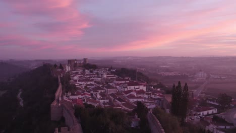 flying close at lighted cross at obidos portugal during sunrise, aerial