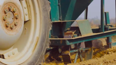 A tractor harrowing in the farm Soil, Low Angle Close up view of big Tyre of the tractor