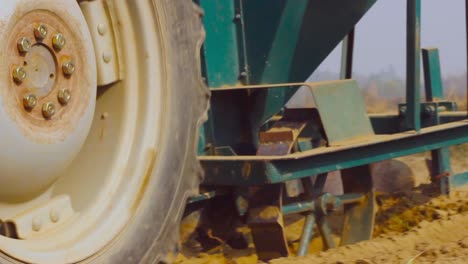 a tractor harrowing in the farm soil, low angle close up view of big tyre of the tractor