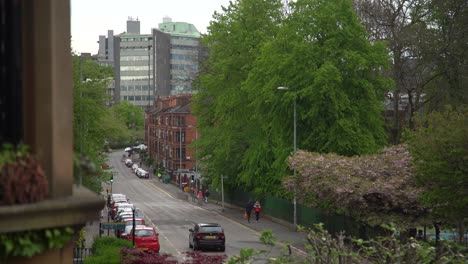 A-cloudy-winter-day-in-Glasgow-West-End-with-buildings,-trees,-cars,-and-people-walking