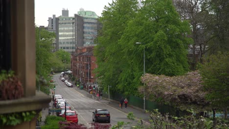 un día nublado de invierno en el extremo oeste de glasgow con edificios, árboles, autos y gente caminando