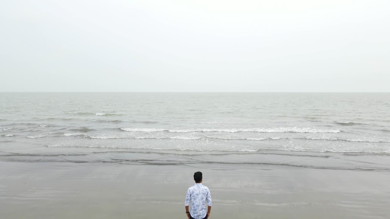 혼자 외로운 남자가 회색 해변에 서있는 나쁜 날씨, 놀라게