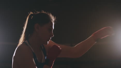 A-strong-athletic,-woman-boxer,-boxing-at-training-on-the-black-background.-Sport-boxing-Concept-with-copy-space.