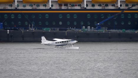 cessna caravan c208 seaplane in the harbor with ships in background