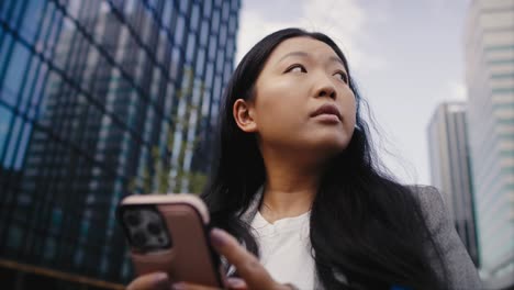 Low-angle-view-of-business-Chinese-woman-holding-mobile-phone