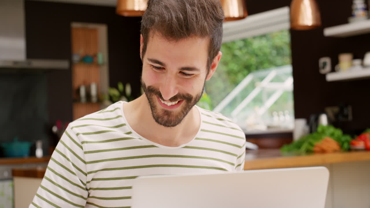 hombre trabajando en una computadora portátil en la cocina