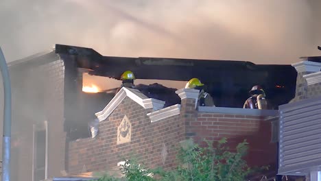 massive smoke raise from living building with firefighters on top, handheld