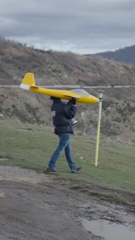 person carrying model airplane on hillside