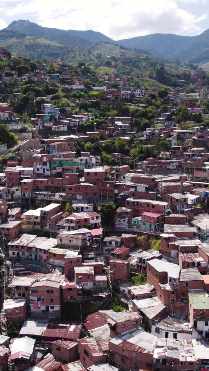 Drone shot capturing the densely populated Comuna 13 neighborhood in Medellin, Colombia, highlighting the colorful houses and urban landscape. Vertical Video
