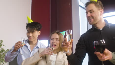 multiethnic colleagues with party hat toasting and drinking at the office party 2