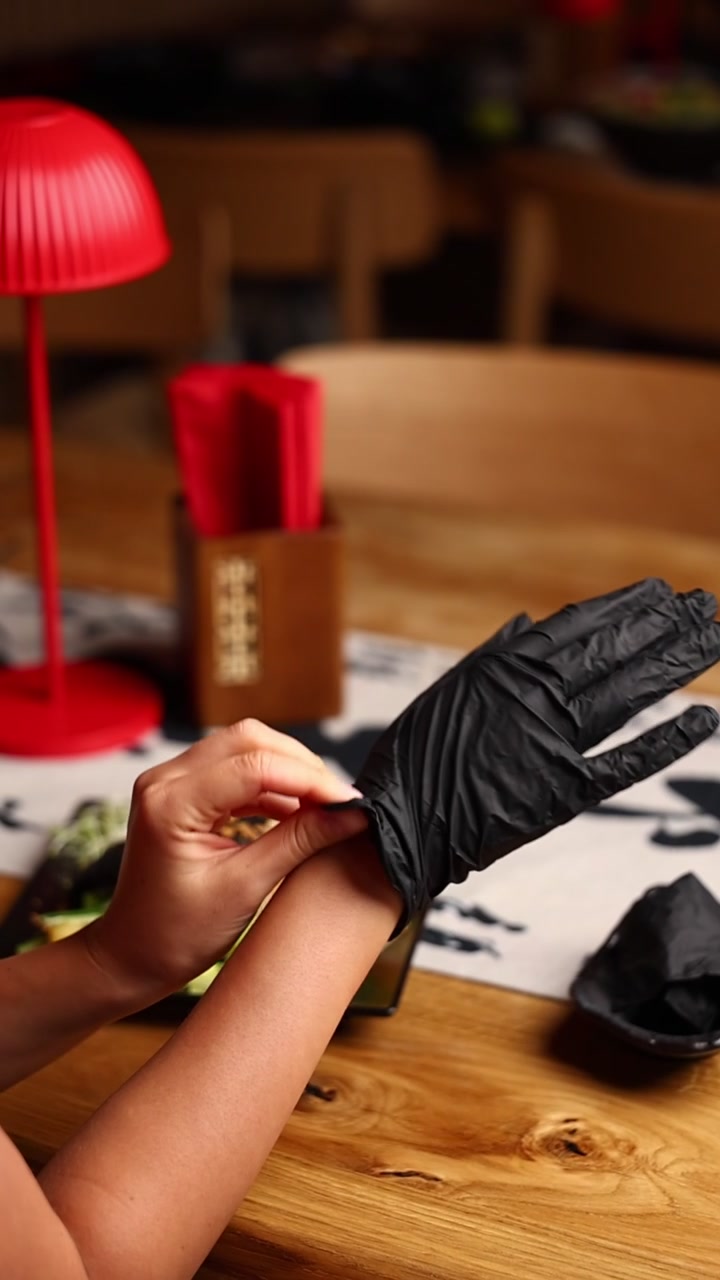 Persona quitándose un guante desechable negro después de preparar comida