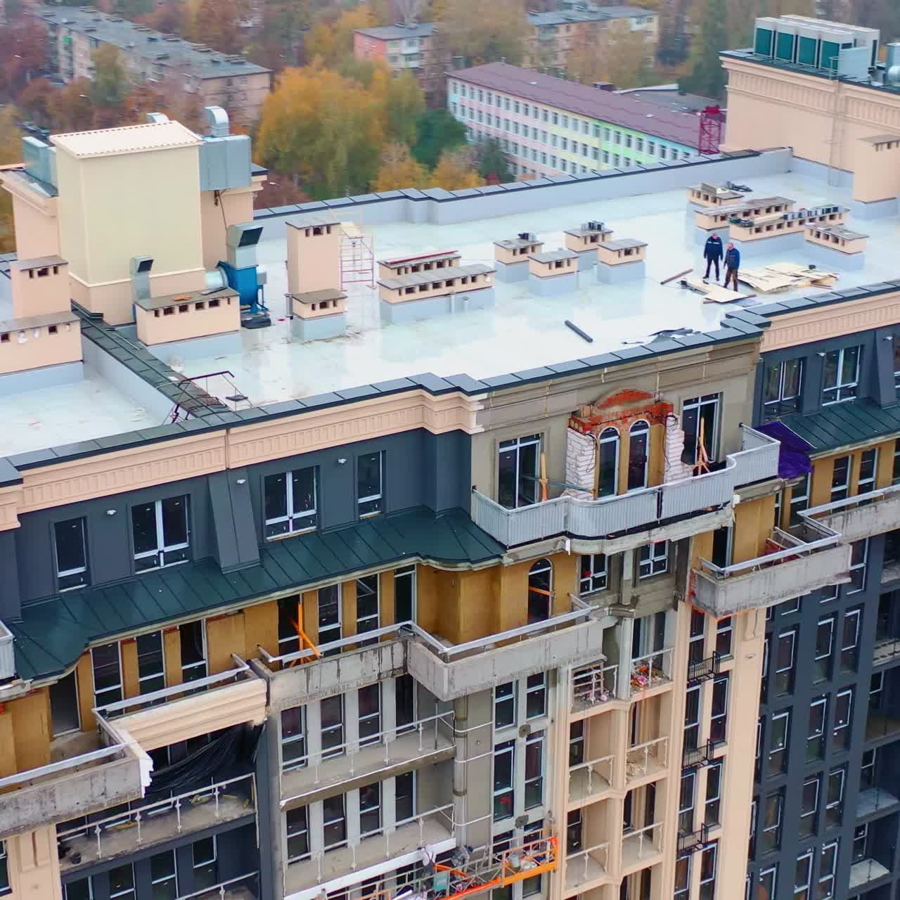 Construction site in the city. Modern architecture is building by workers. High-rise building under construction. Camera moves in a round way. Aerial view.