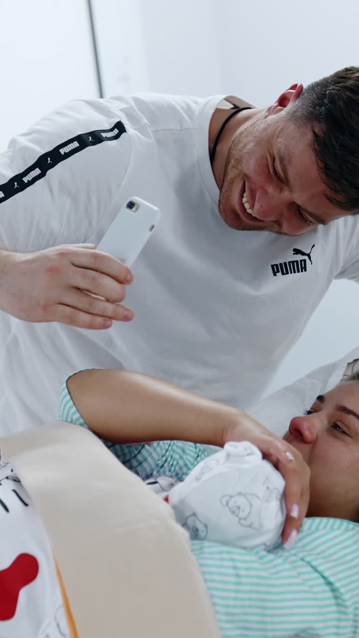 Happy new-made parents speaking through video-chat. Mom holding a baby cries of happiness. Vertical video