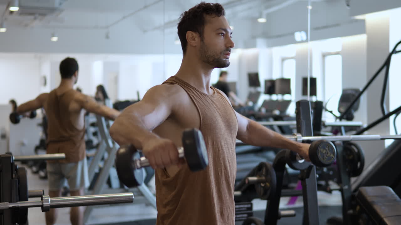 hombre europeo entrenando los hombros con pesas en el gimnasio