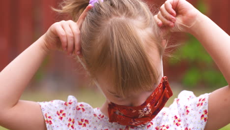 sweet little girl putting on her face mask to protect against coronavirus