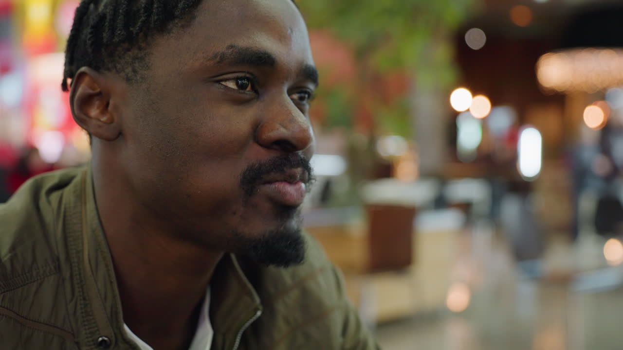 Close up of man biting burger with satisfactory smile, blurred bokeh lights in background, casual dining atmosphere highlighting lifestyle, food enjoyment, and everyday eating