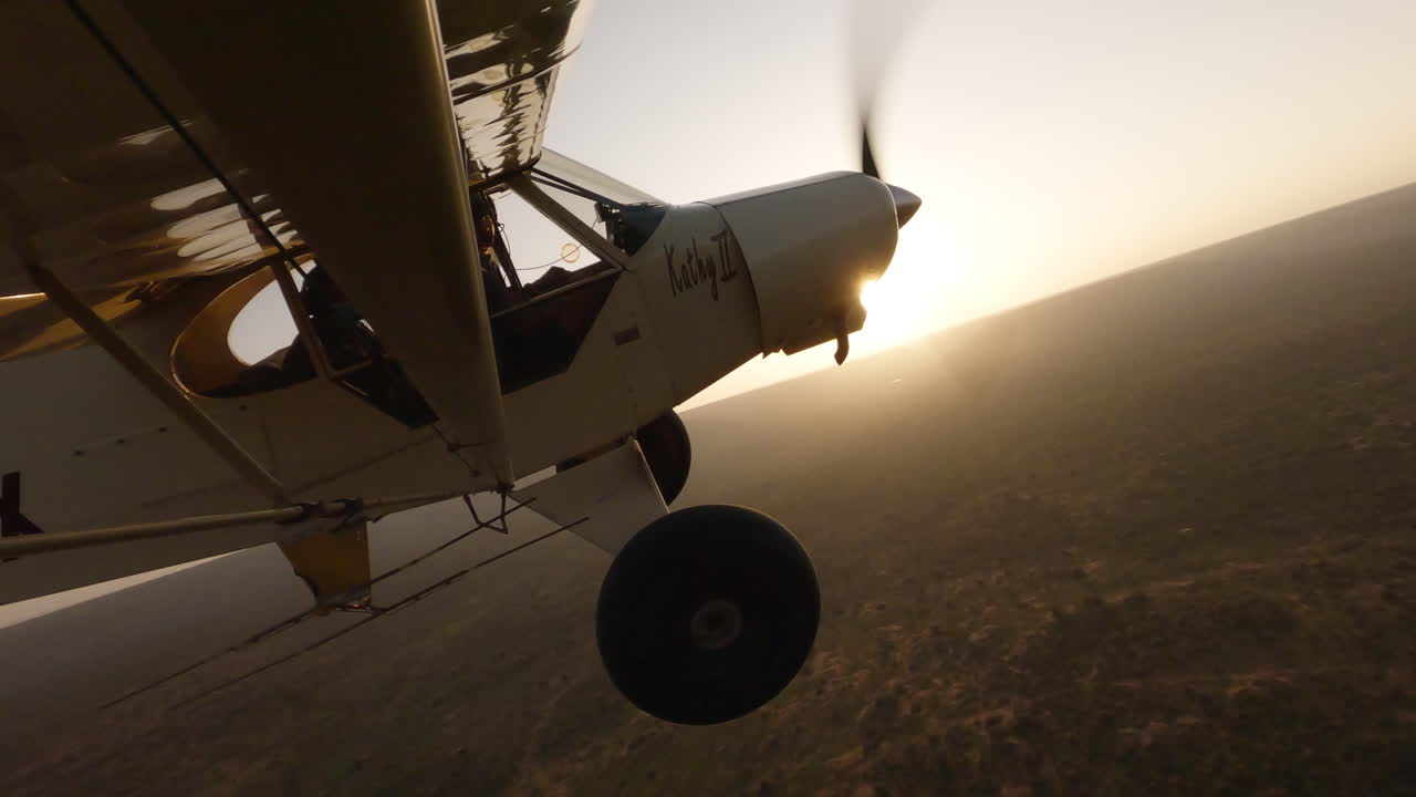 Avião sobrevoando a savana, virando ao encontro do pôr do sol dourado.