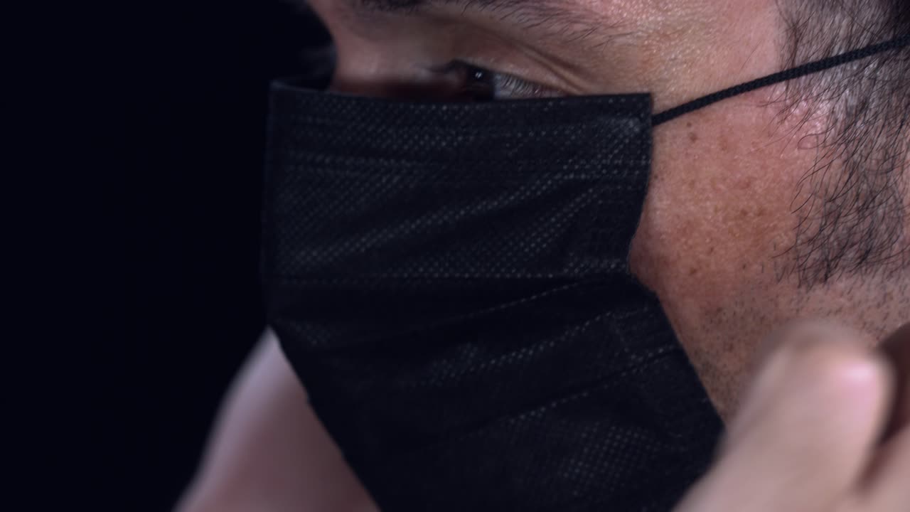 un hombre adulto se pone una mascarilla protectora y la ajusta en la cara