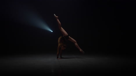 Flexible-girl-doing-somersault-in-dark-space-in-dark-space.-Sportswoman-tumbling