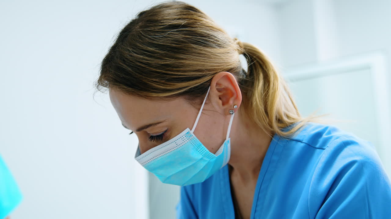 Female medic in mask bends over the newborn baby. Nurse working in the delivery room. Close up.