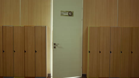 Closeup-white-classroom-door-open-in-empty-hall.-School-interior-with-lockers.