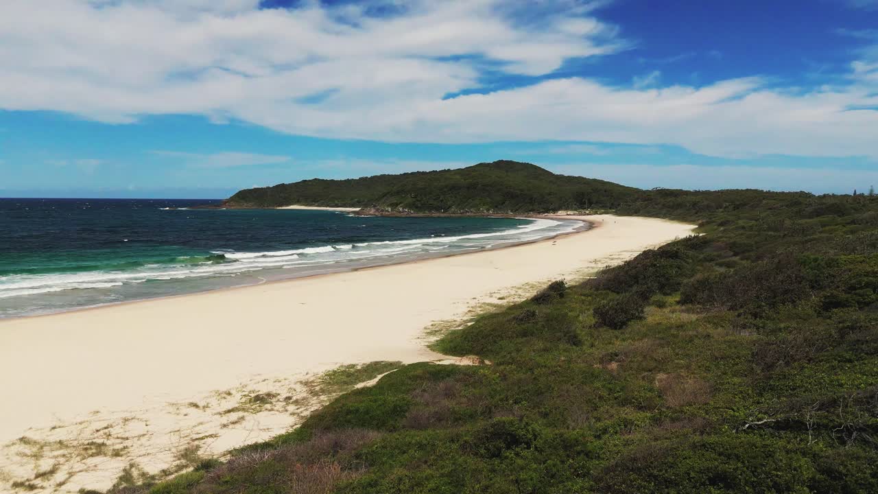 Sandy beach of Booti Booti National Park in New South Wales of Australia. Aerial rising wide shot. Turquoise ocean water and green mountains.