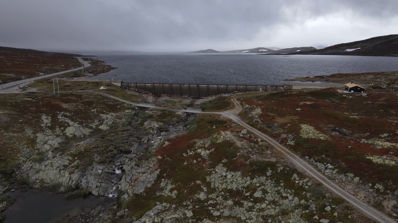 Hardangervidda National park. Drone footage of mountain lake and a dam. Because of high level of the lake water is splashing over the dam