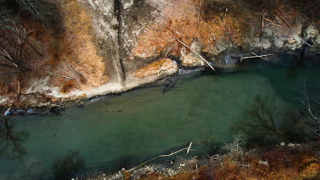 green sediment in water of shallow river stream with sloped silty sandy banks, drone top down