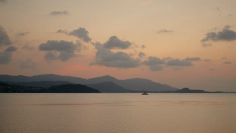 Sunset over the ocean with a sailboat